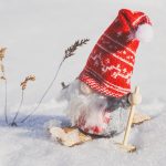 Cute gnome figurine skiing in snowy landscape, adding charm to winter decorations.